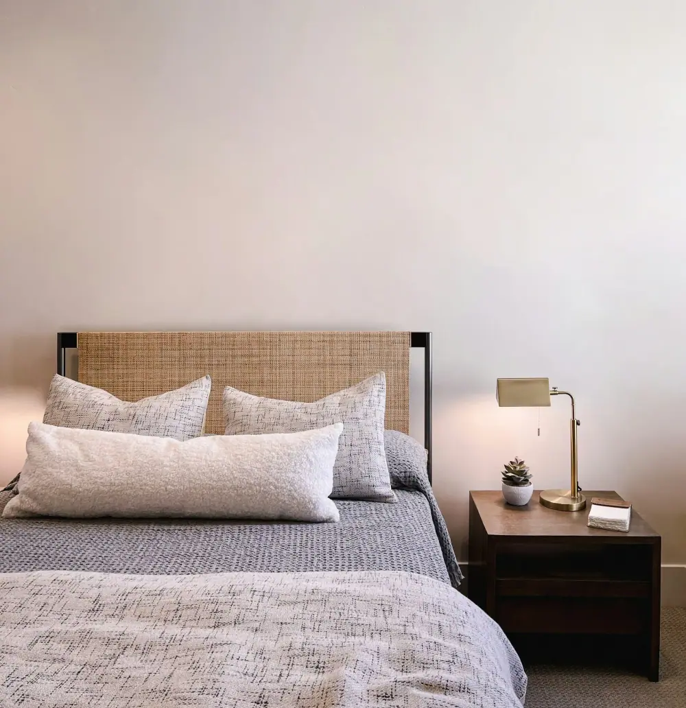 Bett mit geflochtenem Kopfteil und mehreren Kissen für Seitenschläfer